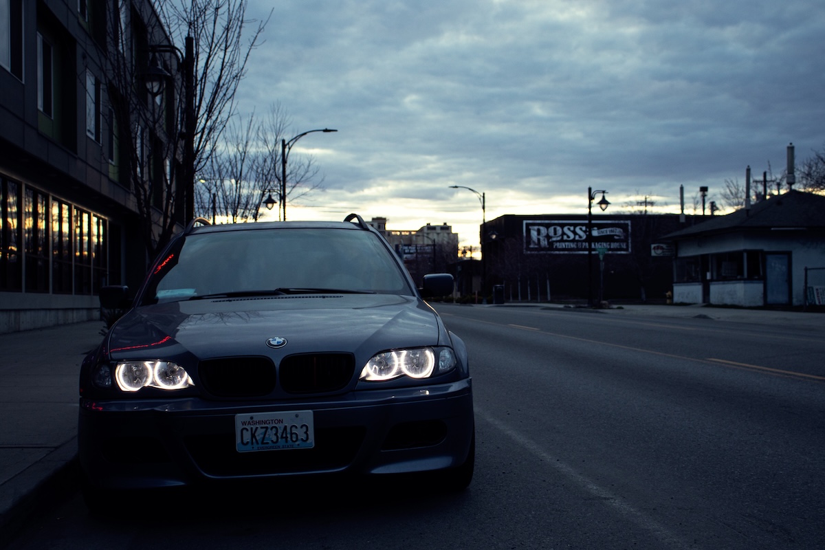 BMW E46 facing forward on empty street at dusk